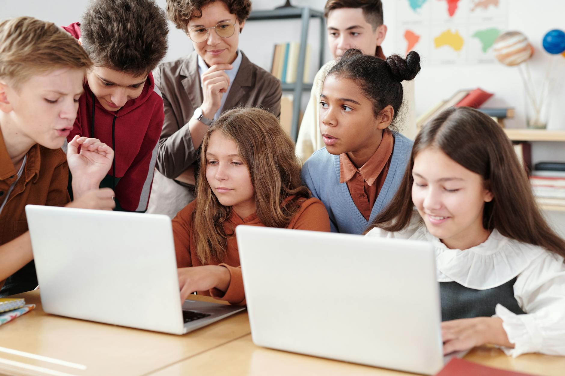 a two girls using laptop with classmates